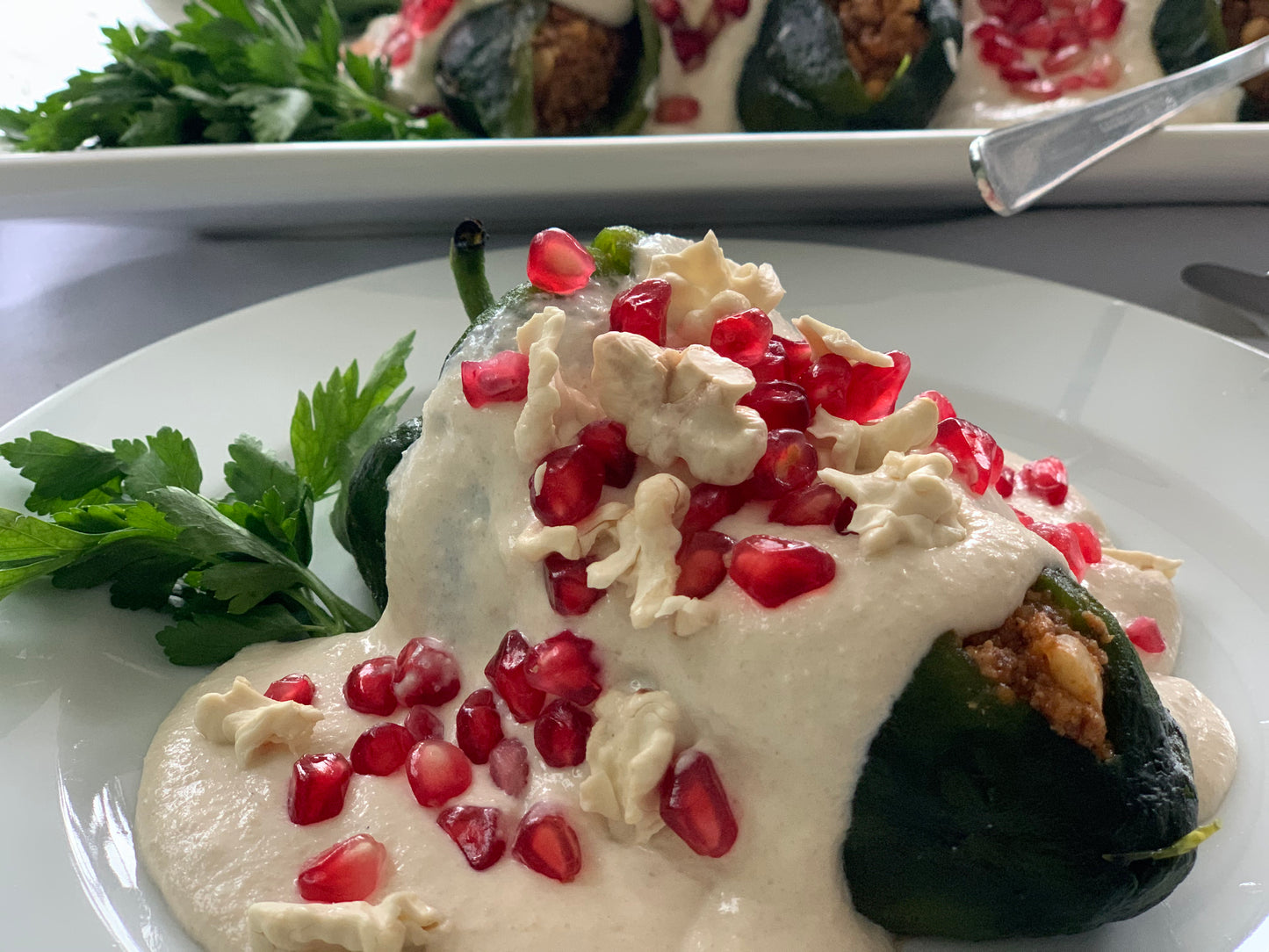 Relleno de carne con fruta, almendras y piñones, bañado con una salsa de nogada acompñadaos con granada fresca